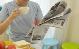 新聞を読みながらコーヒーを飲む男性