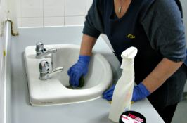 ゴム手袋で洗面所の掃除をする女性
